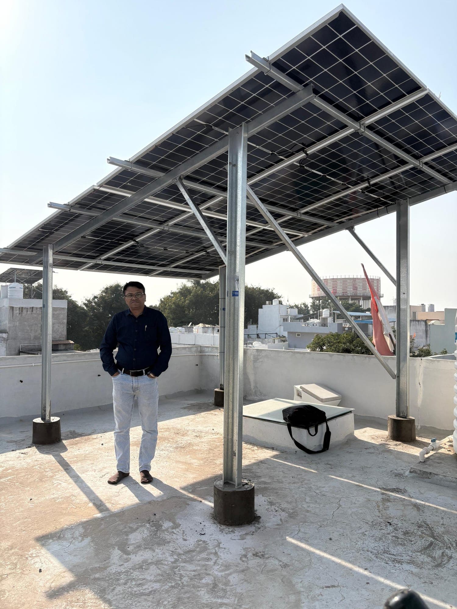 Homeowner standing under his elevated rooftop solar structure in Indore