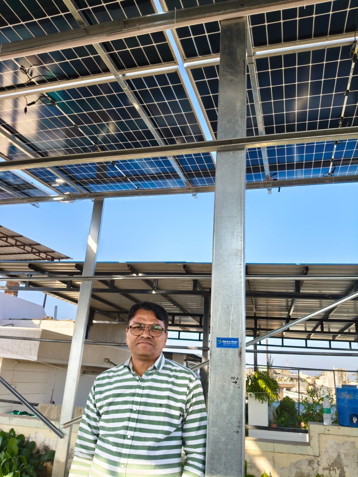 Homeowner under a tall galvanised solar structure above a terrace garden in Indore