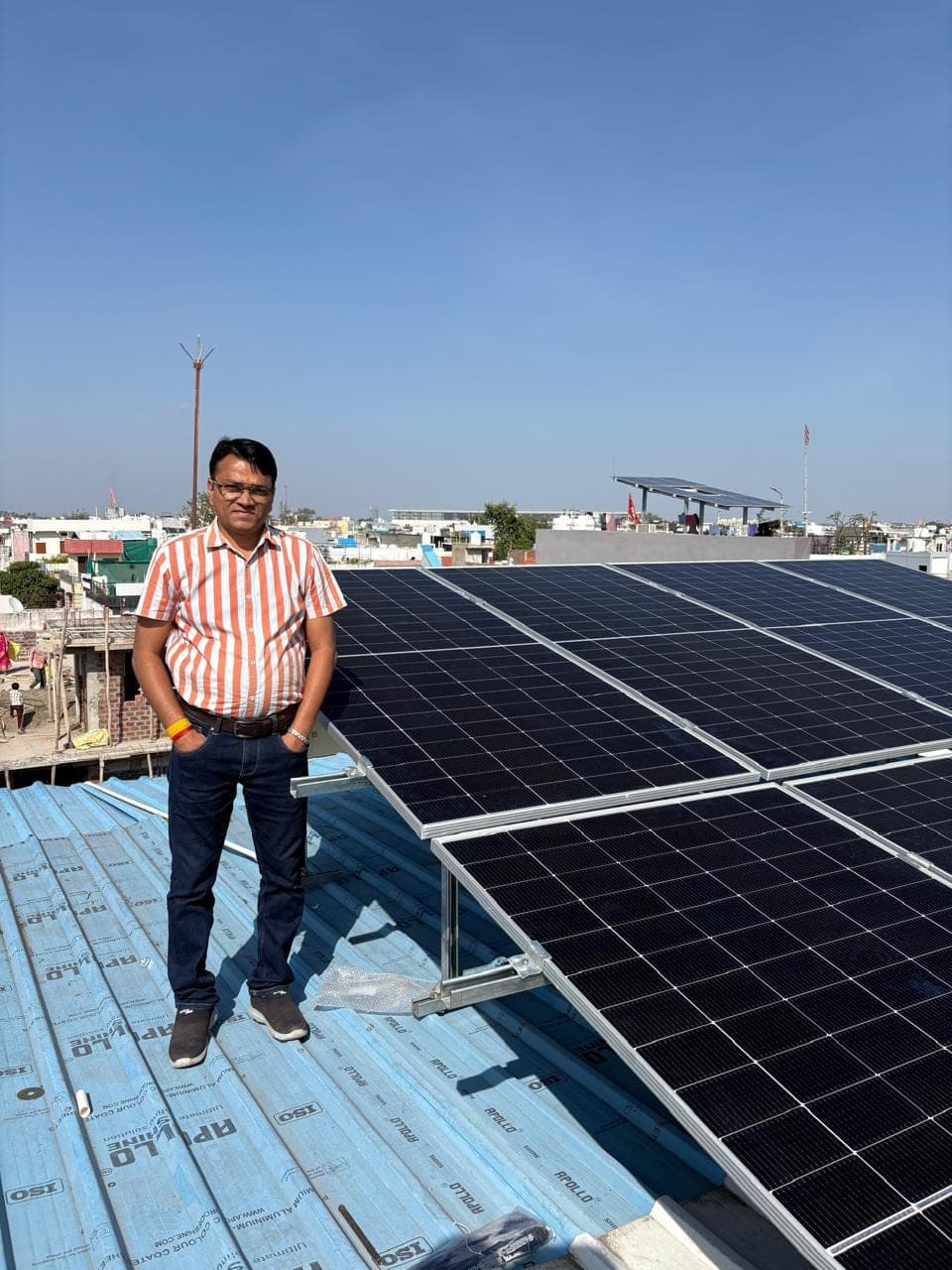 Genius Solar team member beside solar panels mounted on a metal sheet roof in Indore