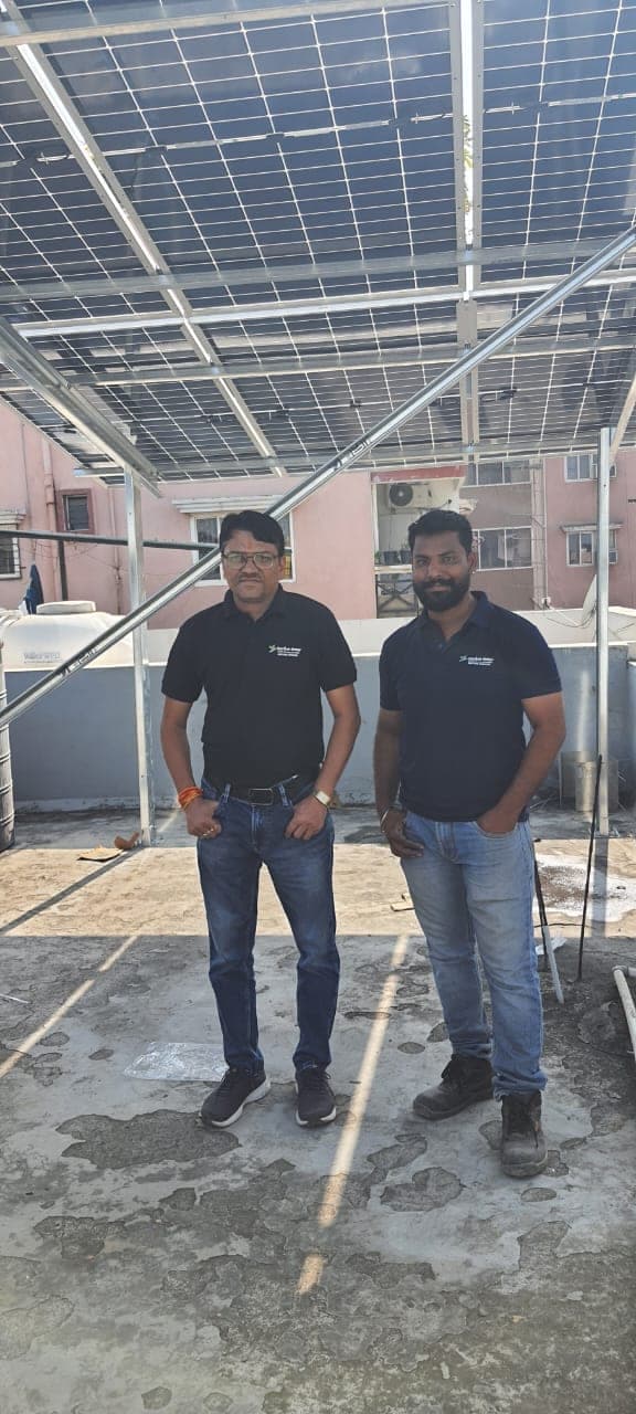 Two Genius Solar engineers under a newly installed elevated solar array in Indore