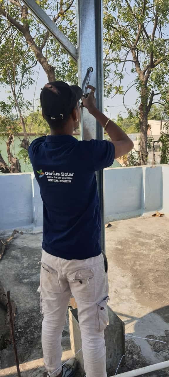 Technician bolting the top bracket of a galvanised solar column on a residential roof in Indore